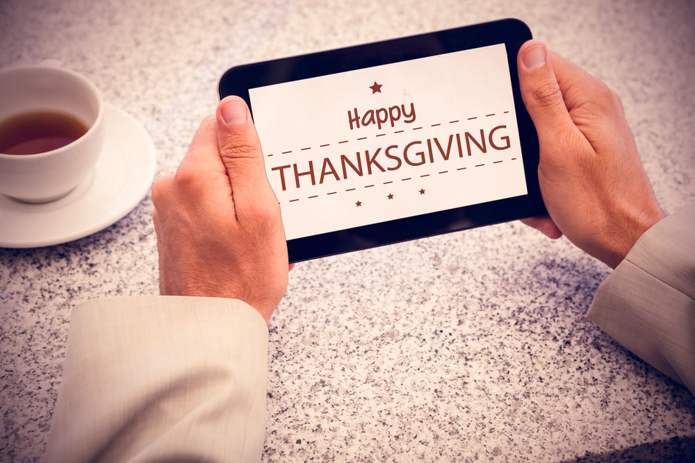 Businessman holding small tablet at table against happy thanksgiving